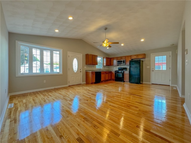 unfurnished living room with a healthy amount of sunlight, lofted ceiling, and light hardwood / wood-style flooring