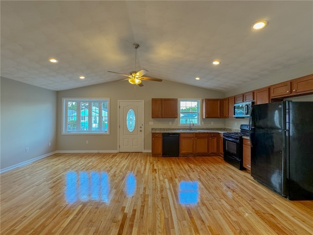 kitchen featuring light hardwood / wood-style flooring, lofted ceiling, black appliances, and sink