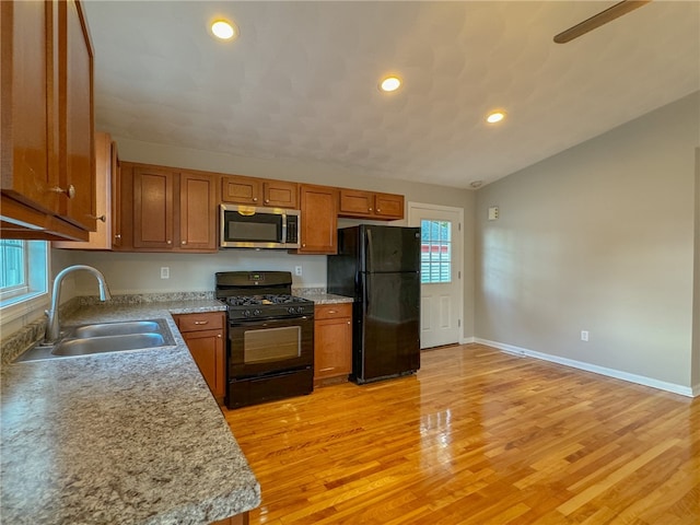 kitchen with vaulted ceiling, light hardwood / wood-style floors, sink, and black appliances