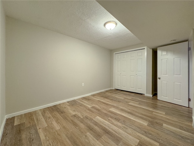 unfurnished bedroom featuring a textured ceiling, light wood-type flooring, and a closet