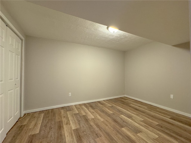 bonus room with light wood-type flooring and a textured ceiling