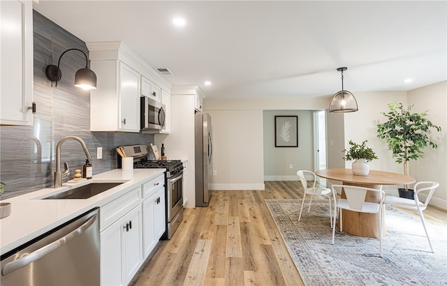 kitchen featuring white cabinets, appliances with stainless steel finishes, sink, and light hardwood / wood-style flooring