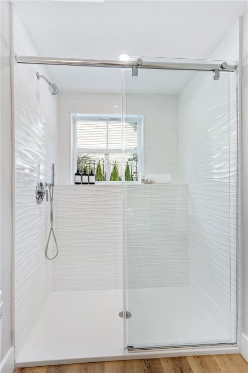 bathroom with wood-type flooring and a shower with shower door