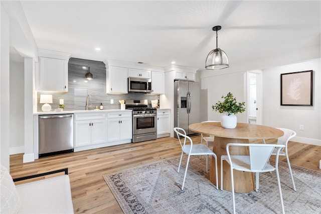 kitchen with appliances with stainless steel finishes, light wood-type flooring, and white cabinets