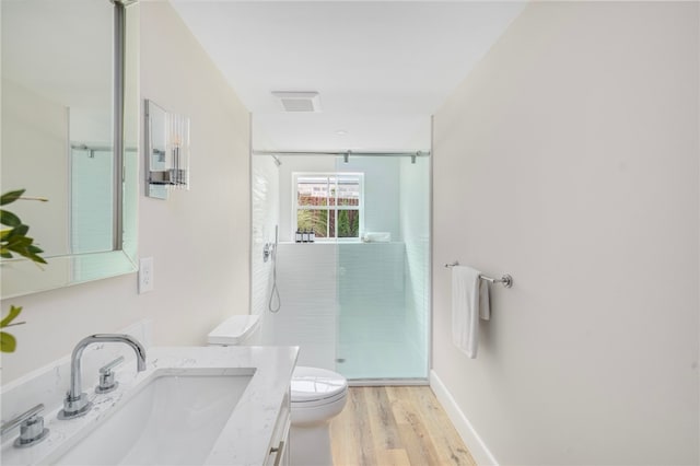 bathroom with vanity, hardwood / wood-style flooring, a shower with shower door, and toilet