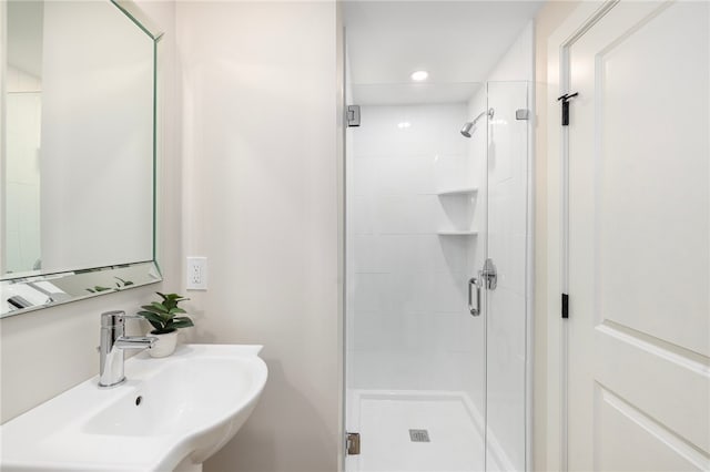 bathroom with a shower with door and sink