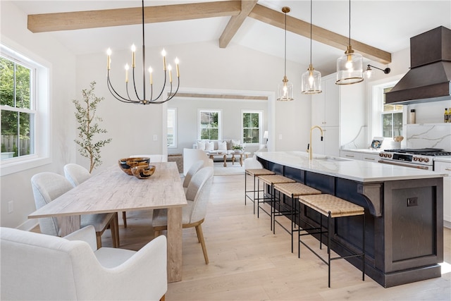 dining area featuring light hardwood / wood-style flooring, lofted ceiling with beams, an inviting chandelier, and sink