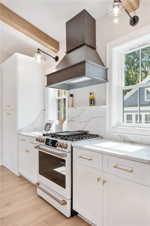 kitchen with light hardwood / wood-style floors, beamed ceiling, white cabinetry, high end white range, and premium range hood