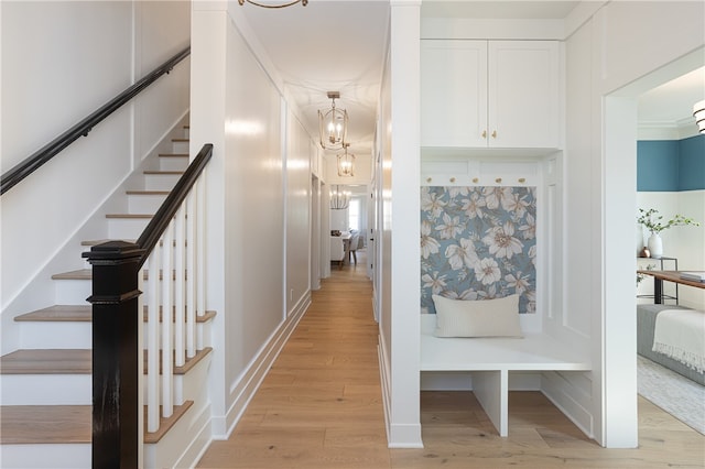 hallway with light hardwood / wood-style flooring, an inviting chandelier, and crown molding