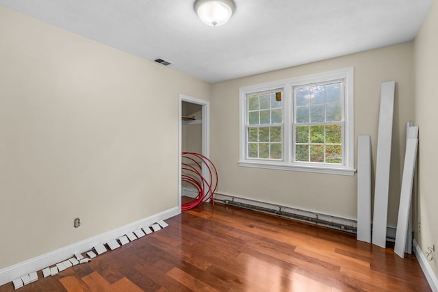 spare room with baseboard heating and dark hardwood / wood-style flooring