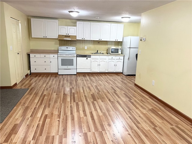 kitchen with light hardwood / wood-style floors, tasteful backsplash, sink, white cabinets, and white appliances