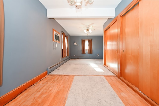 corridor featuring beamed ceiling, a baseboard heating unit, a wall unit AC, and light wood-type flooring