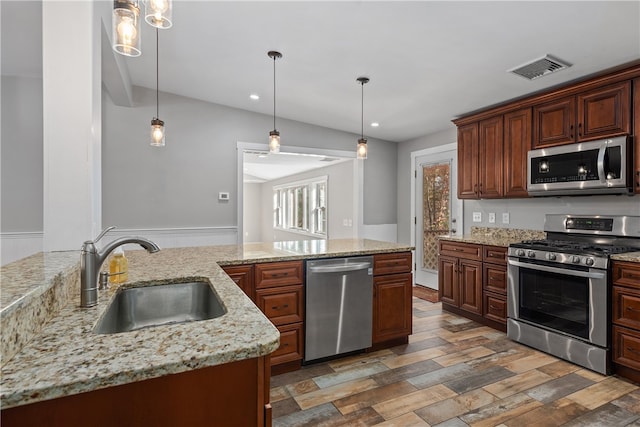 kitchen with dark wood-type flooring, appliances with stainless steel finishes, sink, and hanging light fixtures