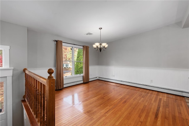 empty room featuring an inviting chandelier, a baseboard radiator, and light wood-type flooring