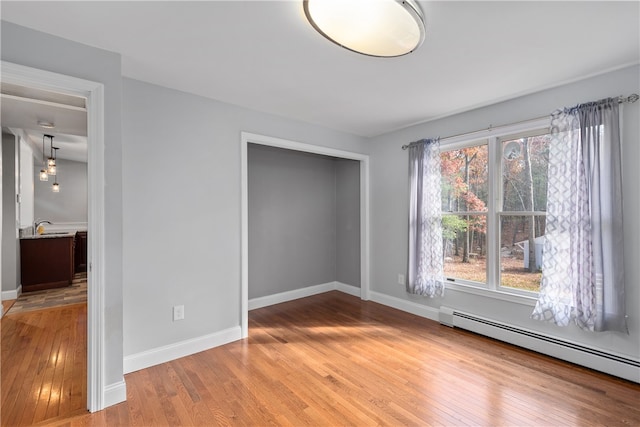 unfurnished bedroom featuring baseboard heating and wood-type flooring