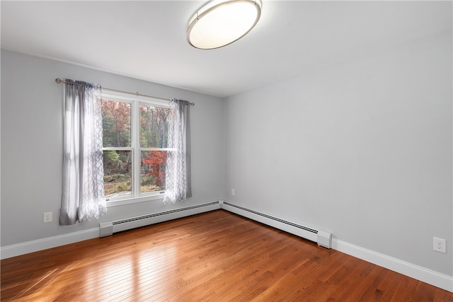 empty room with baseboard heating and hardwood / wood-style floors