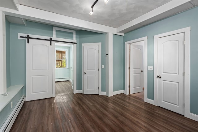 unfurnished bedroom with dark wood-type flooring, a barn door, and a baseboard heating unit