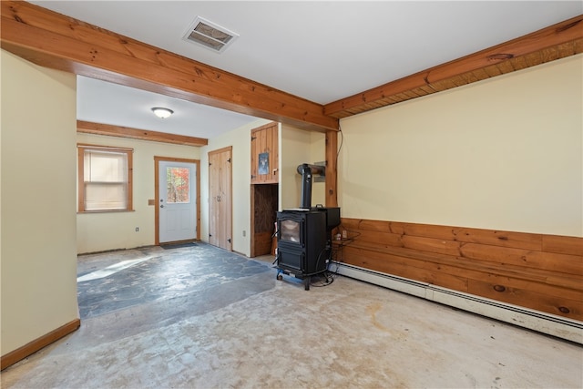 entryway featuring a baseboard heating unit, concrete flooring, and a wood stove