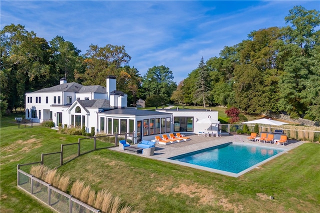 back of property featuring a patio, a fenced in pool, and a lawn