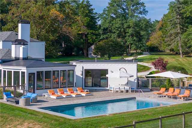 back of property with french doors, a fenced in pool, a yard, and a patio