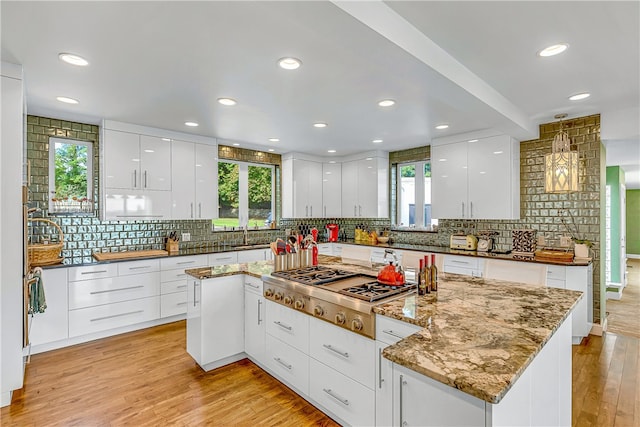 kitchen featuring light wood-type flooring, plenty of natural light, a center island, and white cabinets