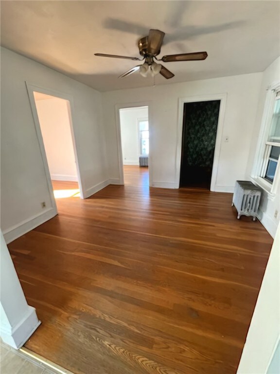 unfurnished room featuring ceiling fan, hardwood / wood-style floors, and radiator