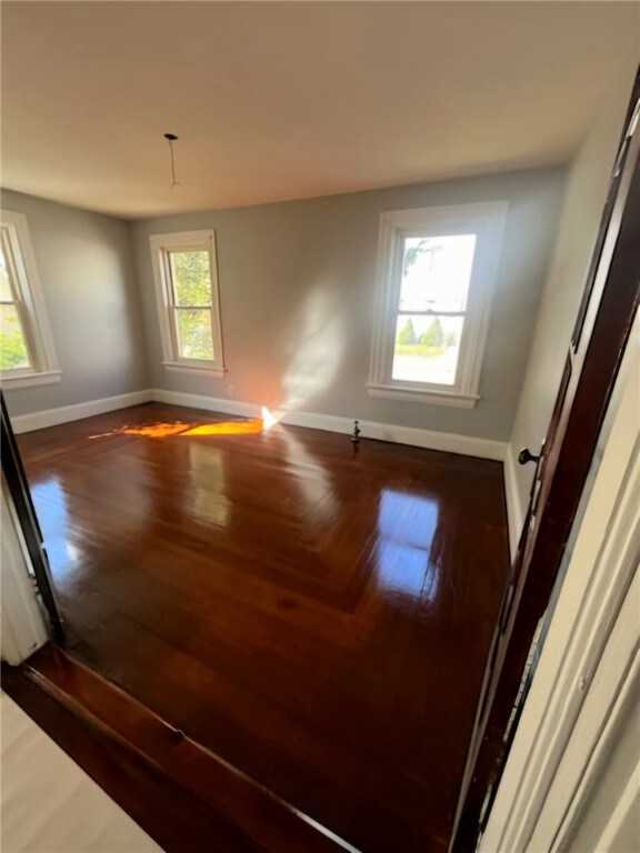 spare room with dark wood-type flooring and a healthy amount of sunlight