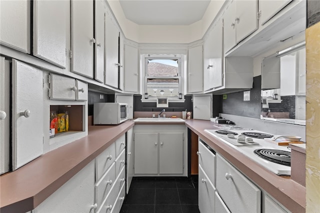 kitchen with white appliances, white cabinetry, sink, and dark tile patterned flooring