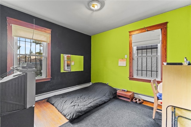 bedroom with hardwood / wood-style floors and a baseboard radiator