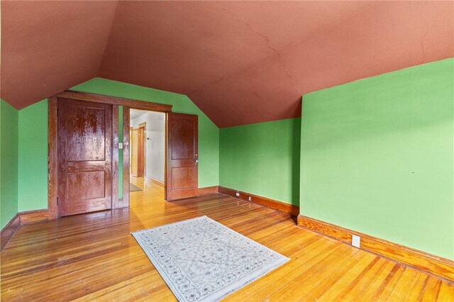 additional living space with lofted ceiling and hardwood / wood-style floors