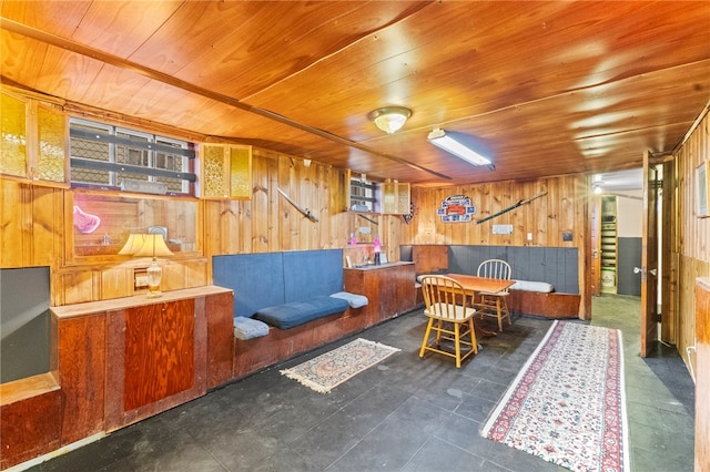 interior space with dark tile patterned floors, wooden walls, and wooden ceiling