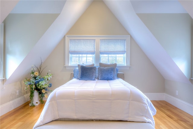 bedroom with vaulted ceiling and light wood-type flooring