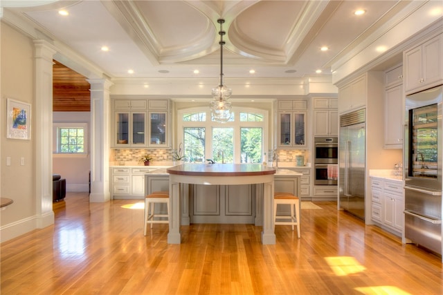 kitchen featuring a kitchen island, decorative light fixtures, light hardwood / wood-style flooring, stainless steel appliances, and a kitchen breakfast bar