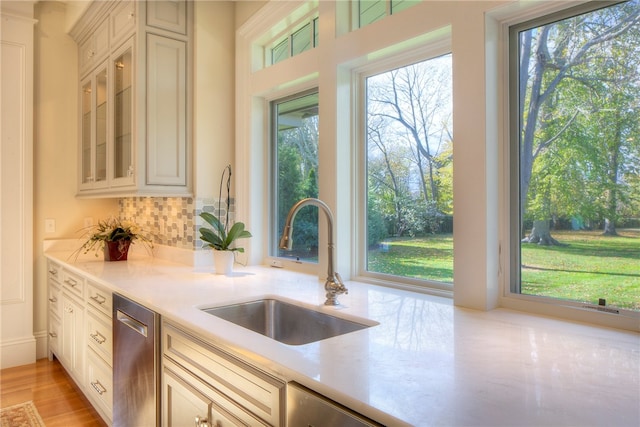 kitchen with stainless steel dishwasher, backsplash, sink, and a wealth of natural light