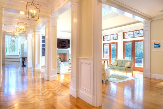 hallway featuring french doors, light hardwood / wood-style floors, crown molding, and ornate columns