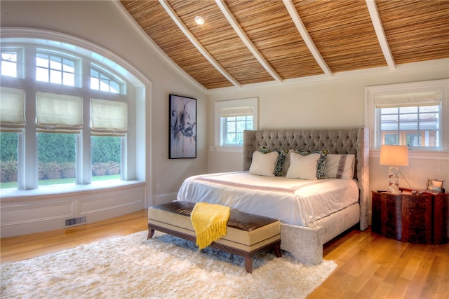 bedroom with light wood-type flooring, vaulted ceiling with beams, and wooden ceiling