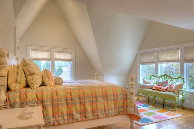 bedroom with vaulted ceiling, hardwood / wood-style floors, and multiple windows