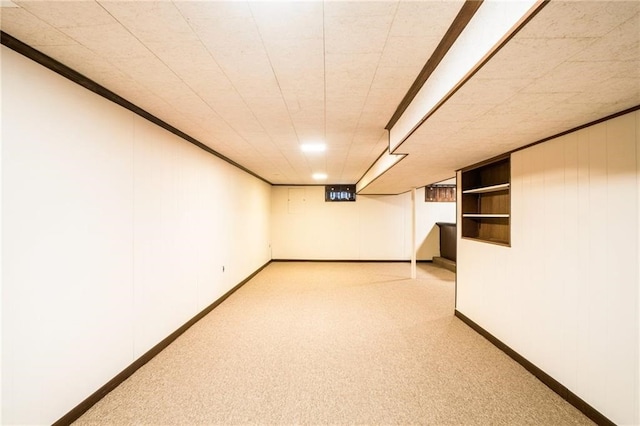 basement with ornamental molding and light carpet