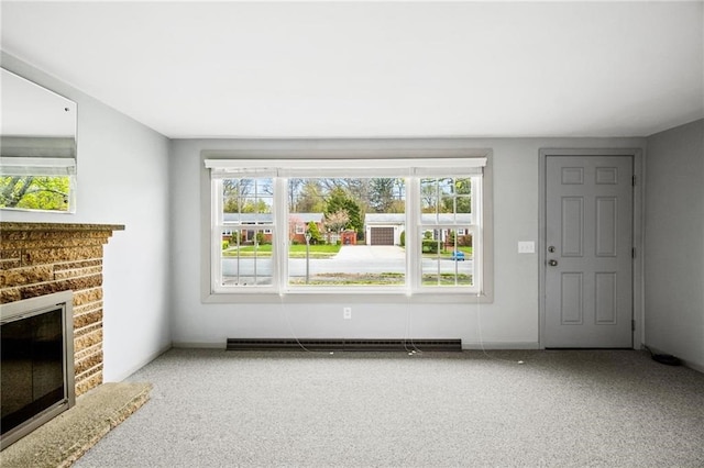 unfurnished living room with a brick fireplace, baseboard heating, and carpet floors