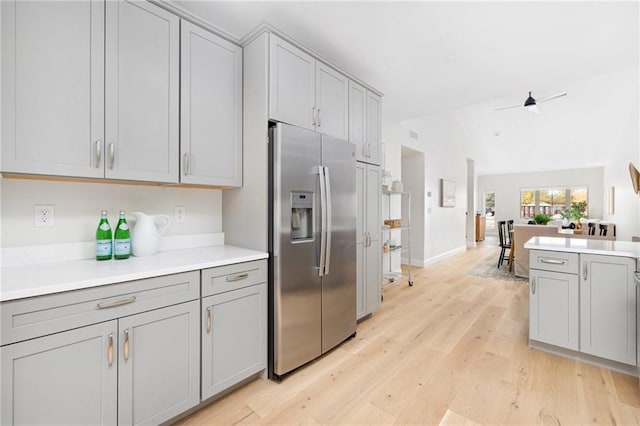 kitchen with gray cabinetry, light hardwood / wood-style flooring, lofted ceiling, and stainless steel fridge