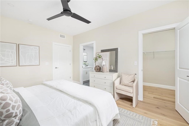 bedroom with ceiling fan, a spacious closet, light hardwood / wood-style floors, a closet, and ensuite bath