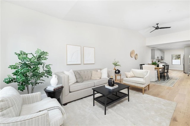 living room featuring light hardwood / wood-style flooring, ceiling fan, and vaulted ceiling