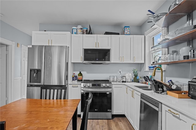 kitchen featuring appliances with stainless steel finishes, light wood-type flooring, and white cabinetry