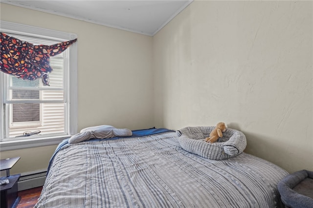 bedroom featuring ornamental molding, hardwood / wood-style floors, and a baseboard heating unit