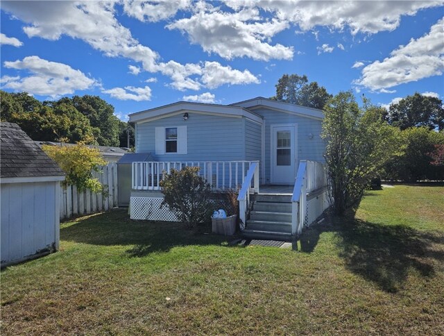 back of property with a wooden deck, a yard, and a shed