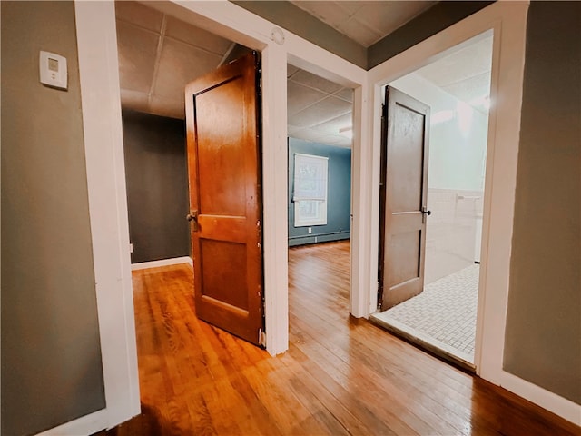 corridor with hardwood / wood-style floors and a baseboard heating unit