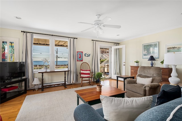 living room with ceiling fan, ornamental molding, a baseboard heating unit, and light wood-type flooring