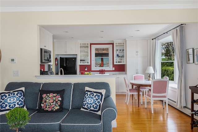 kitchen with black refrigerator, light wood-type flooring, white cabinets, and ornamental molding