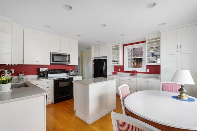 kitchen with sink, a center island, white cabinets, black appliances, and light wood-type flooring