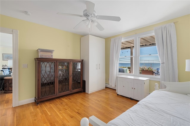 bedroom featuring ceiling fan, a baseboard radiator, and light hardwood / wood-style flooring